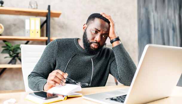 stressed man at desk looking at computer